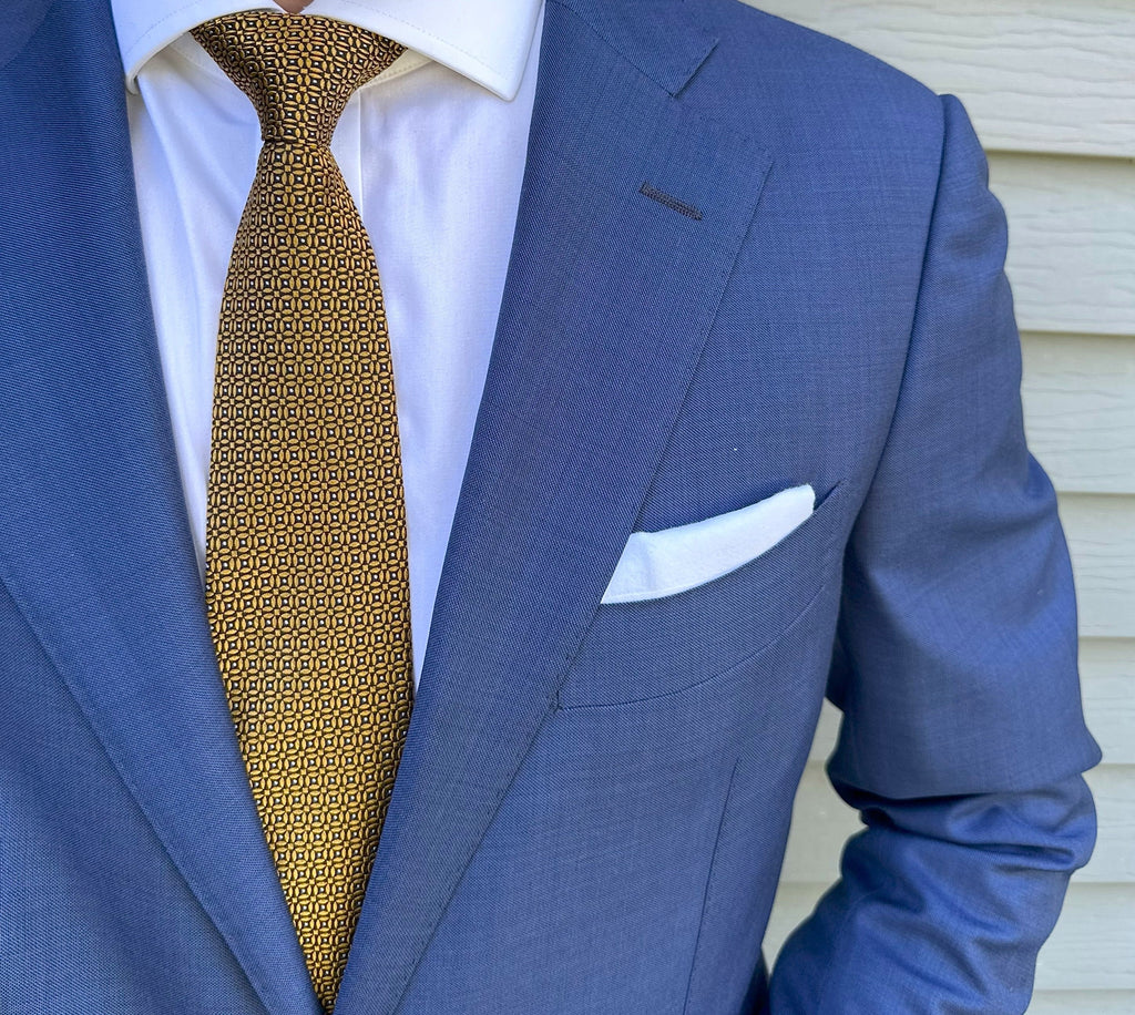 Gold silk necktie with a neat repeating circle motif, close detail