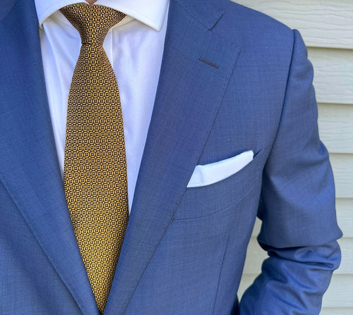 Gold silk necktie with a neat repeating circle motif, close detail