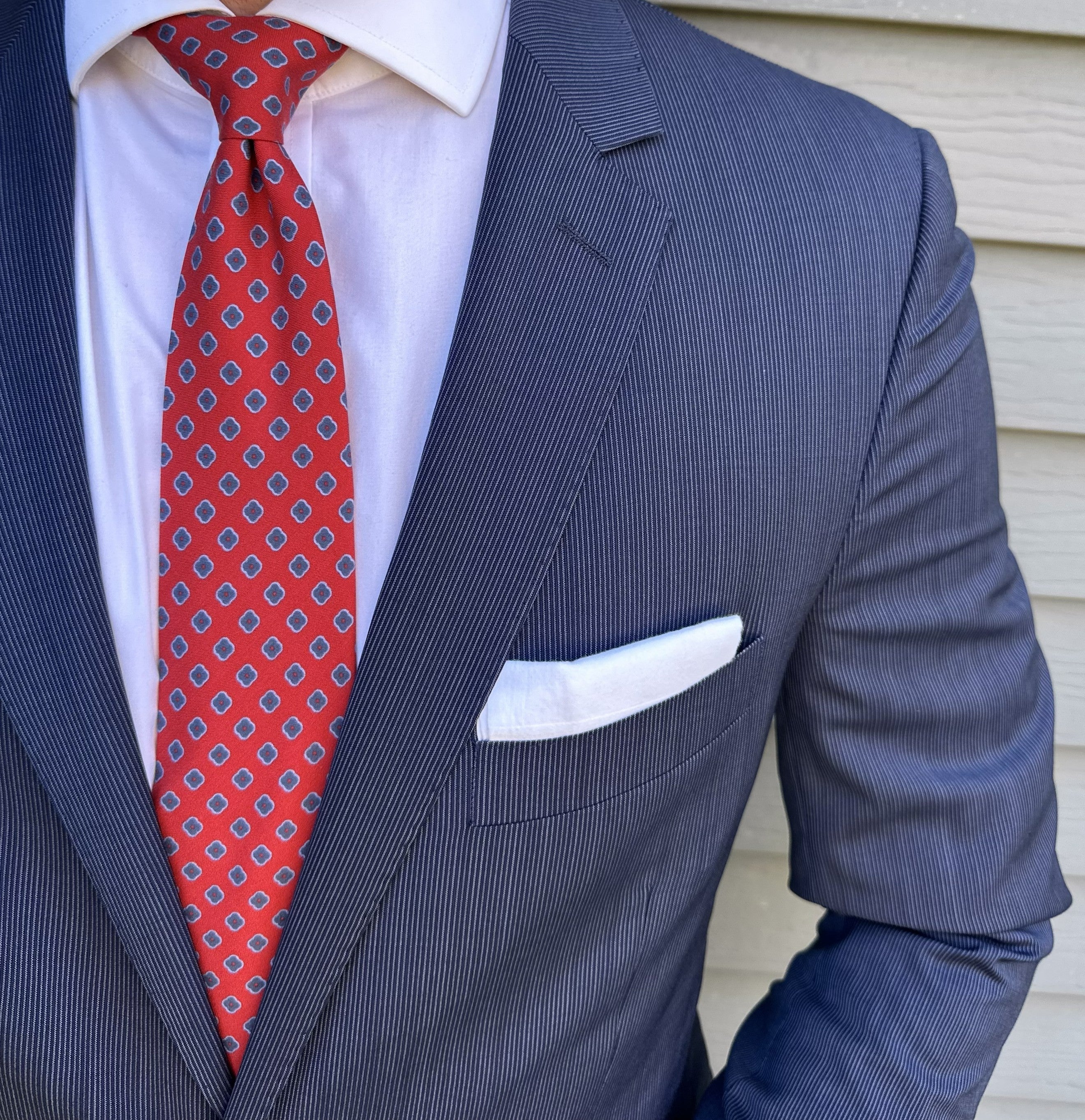 Red foulard silk necktie photographed flat against a neutral ground