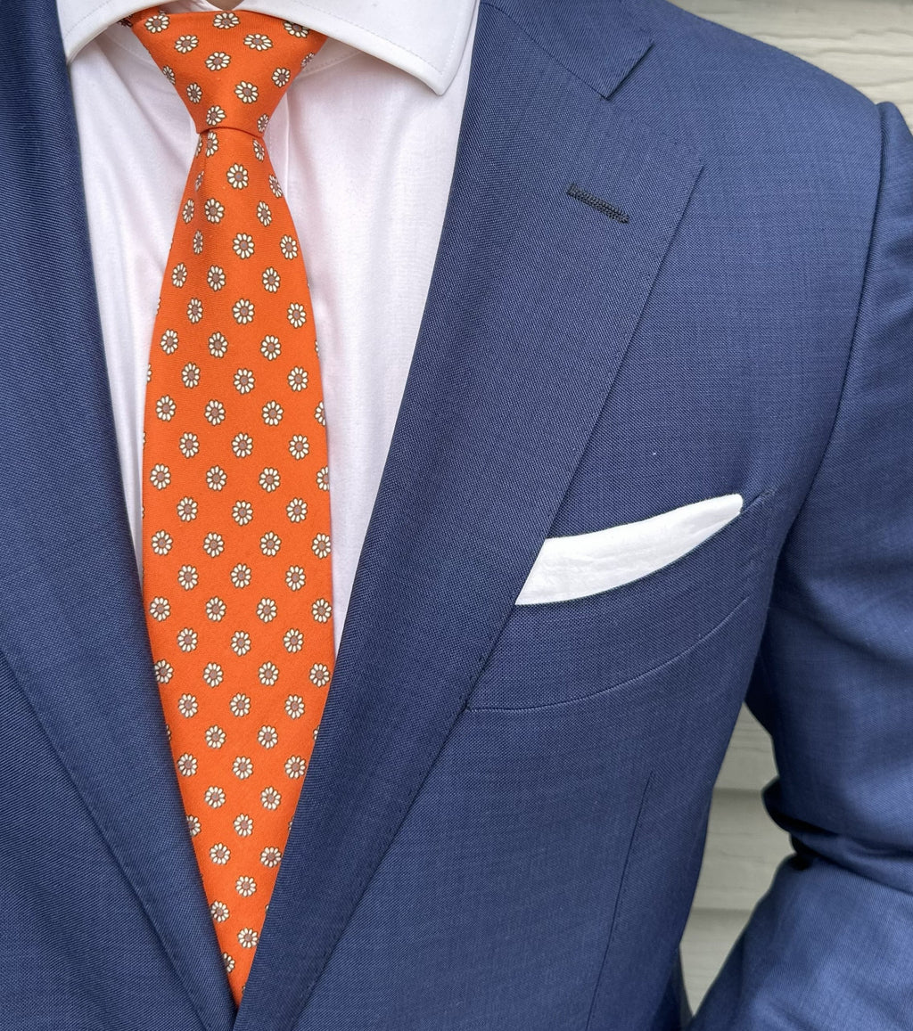 Orange foulard silk necktie with a fine repeating motif, shown flat