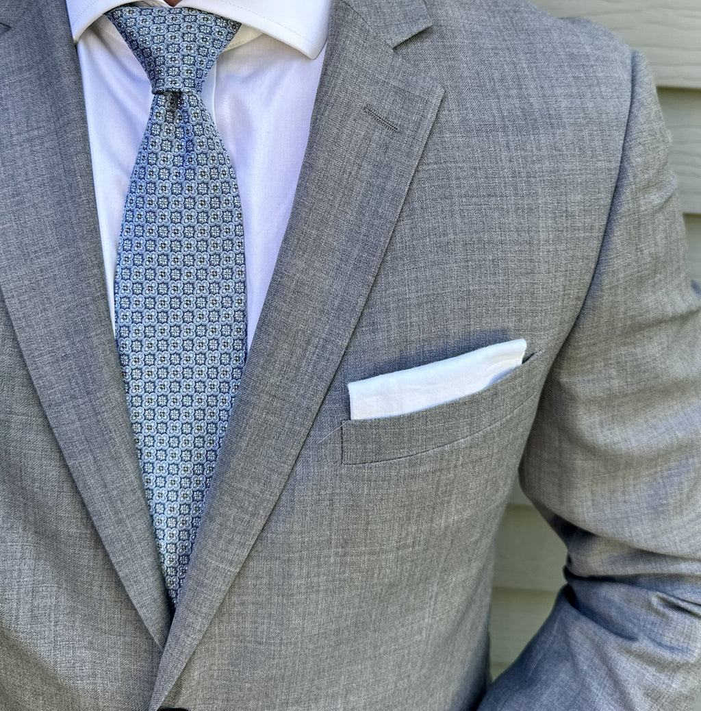 Blue foulard silk necktie with a small repeating motif, shown flat