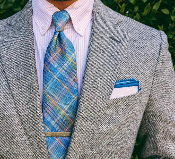 Teal plaid silk necktie photographed flat, check pattern visible