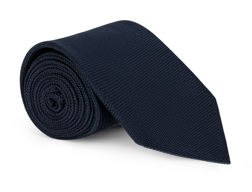Plain navy silk necktie shown knotted against a pale background