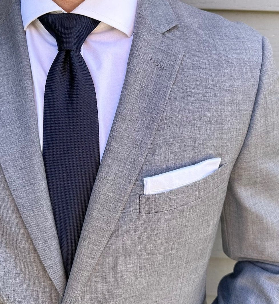 Plain navy silk necktie shown knotted against a pale background