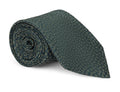 Green floral patterned silk necktie laid flat on a pale background