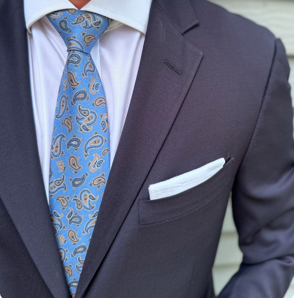 Light blue paisley silk necktie laid flat, paisley repeat in view