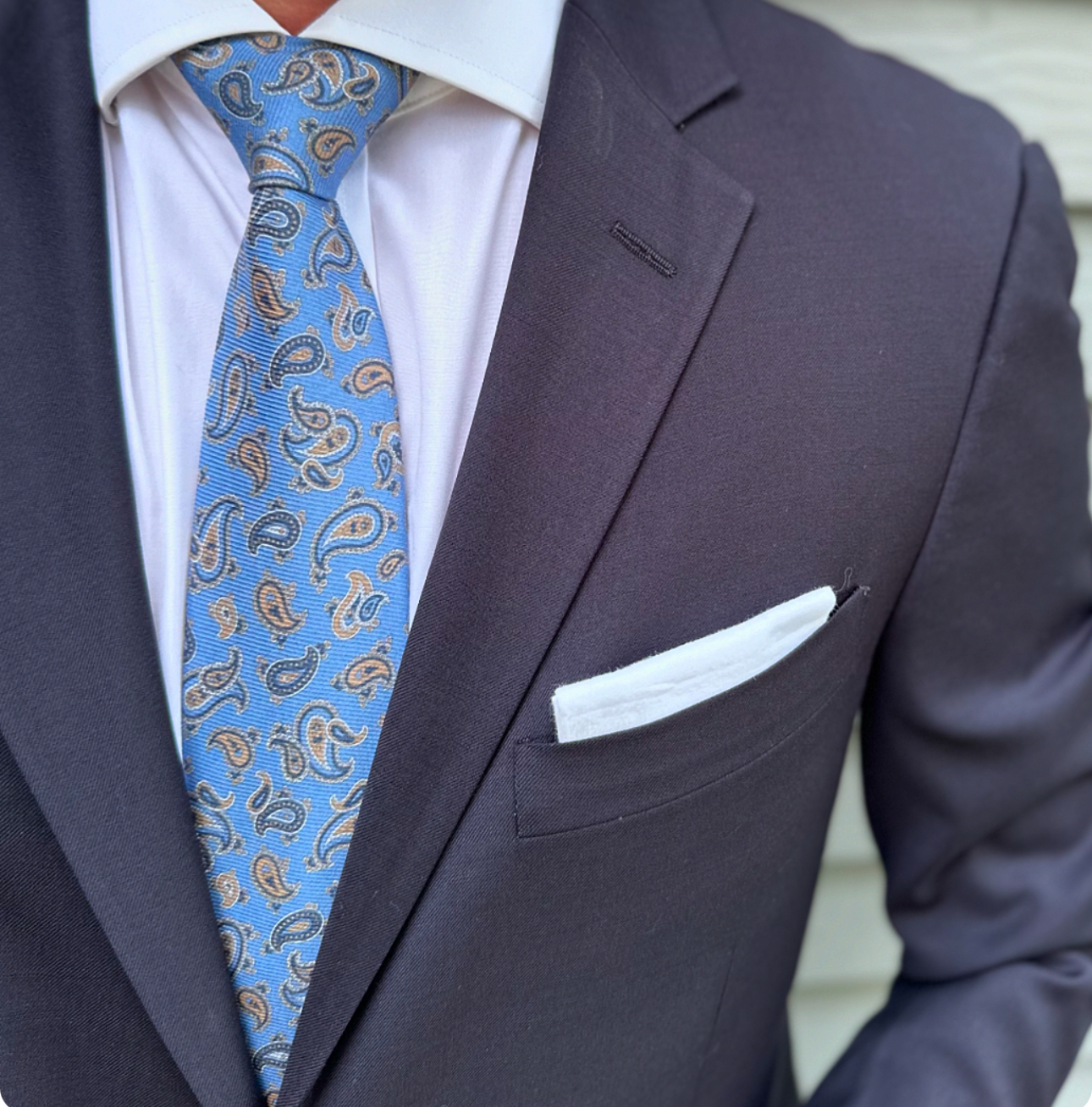 Light blue paisley silk necktie laid flat, paisley repeat in view