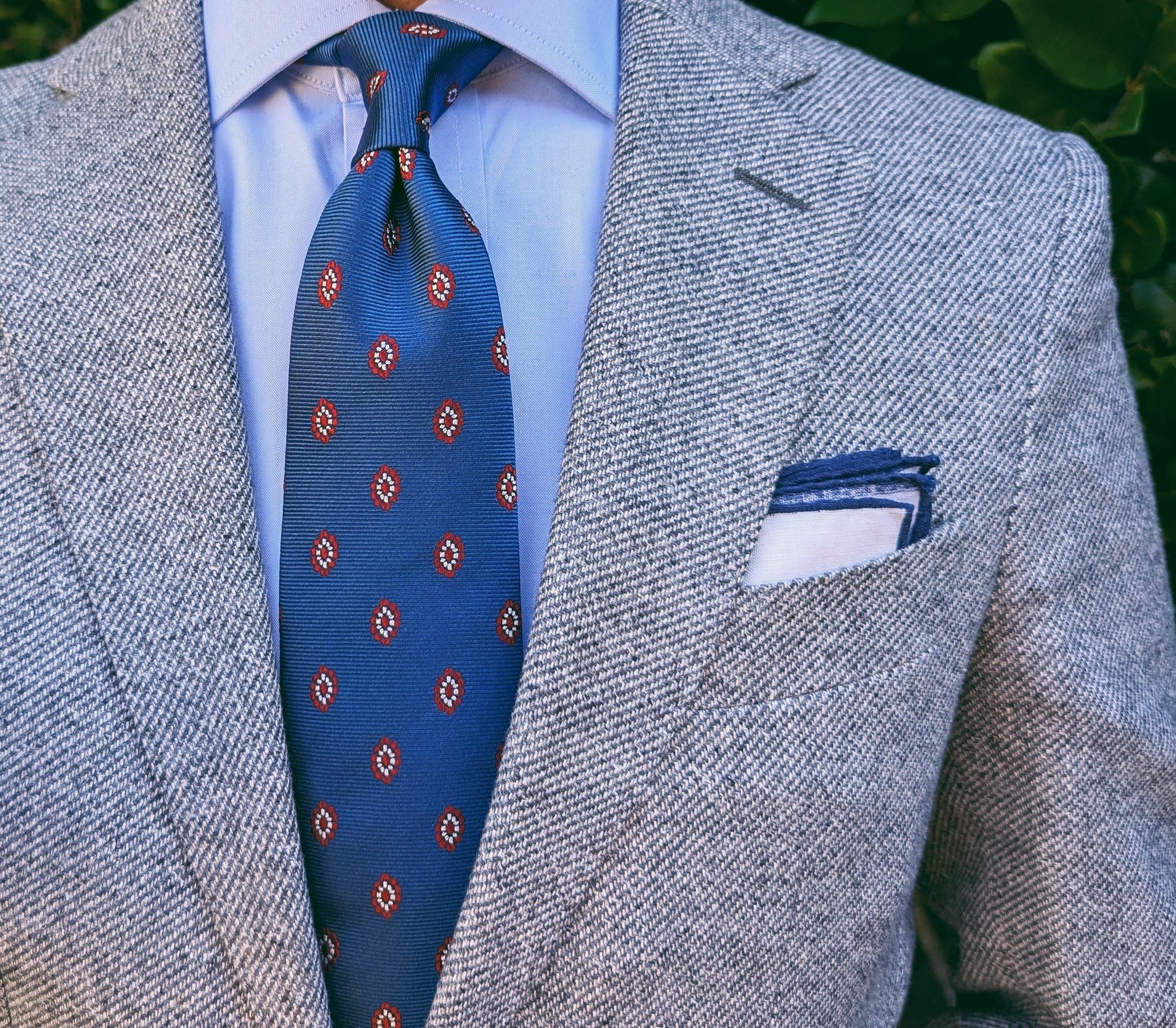 Blue silk necktie with a repeating medallion motif, laid flat