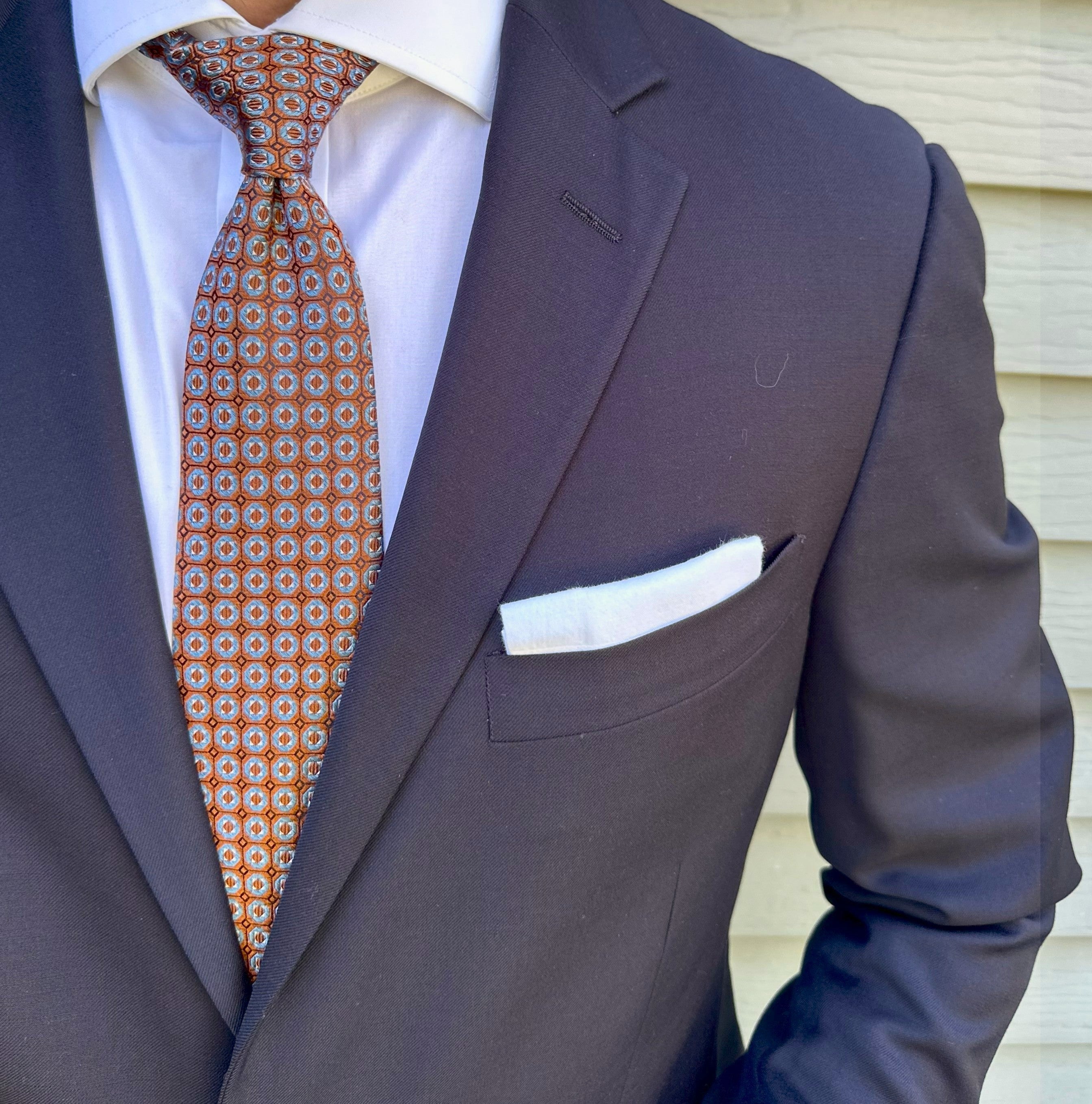 Orange geometric patterned silk necktie shown flat on a light ground