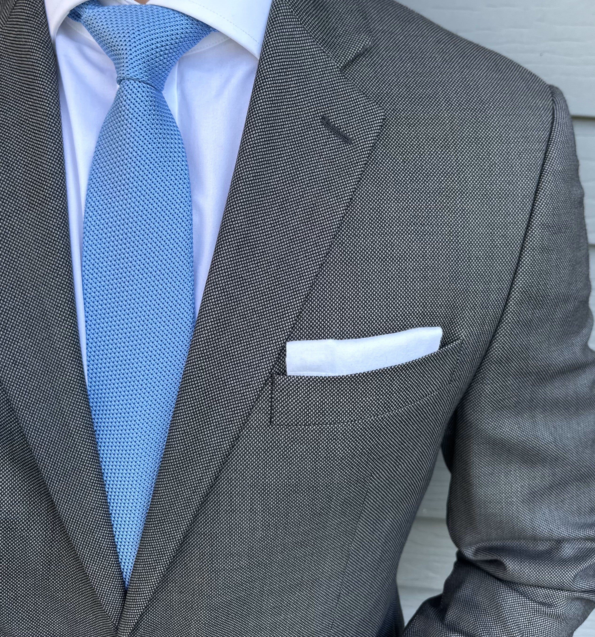 Mid-blue grenadine silk necktie with an open textured weave, shown flat