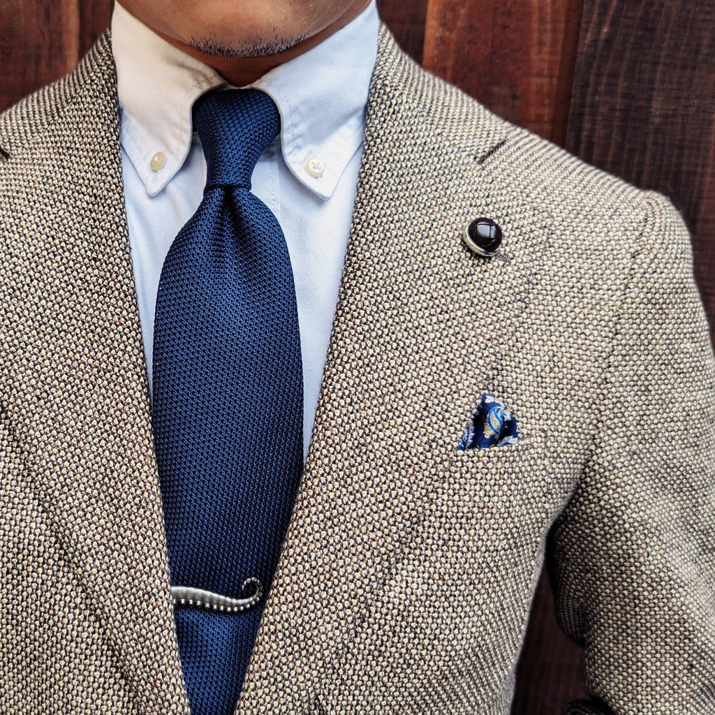Navy grenadine silk necktie photographed flat, textured weave in detail