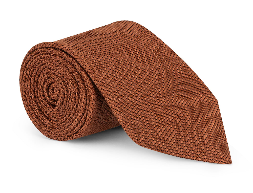 Rust orange grenadine silk necktie laid flat against a light background