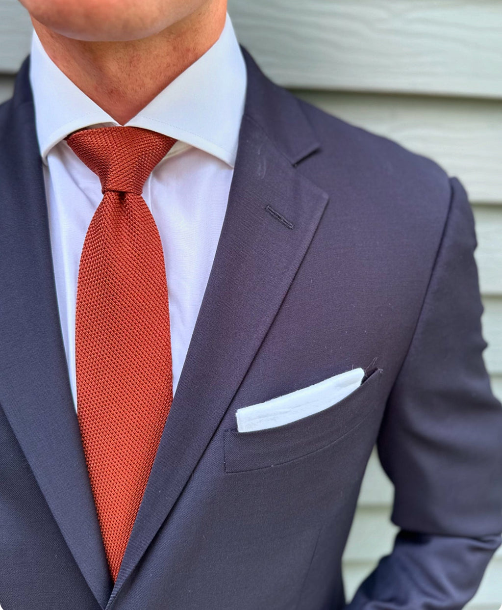 Rust orange grenadine silk necktie laid flat against a light background