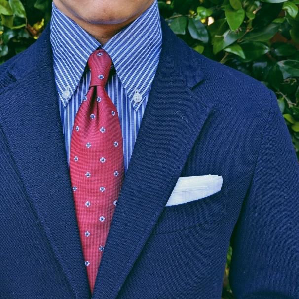 Red foulard silk necktie with a classic repeating pattern, shown flat
