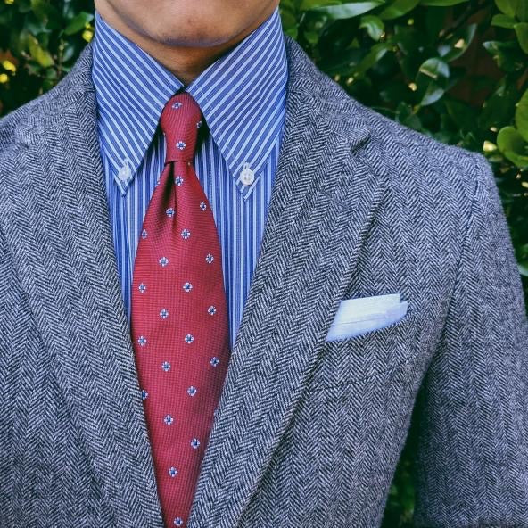 Red foulard silk necktie with a classic repeating pattern, shown flat
