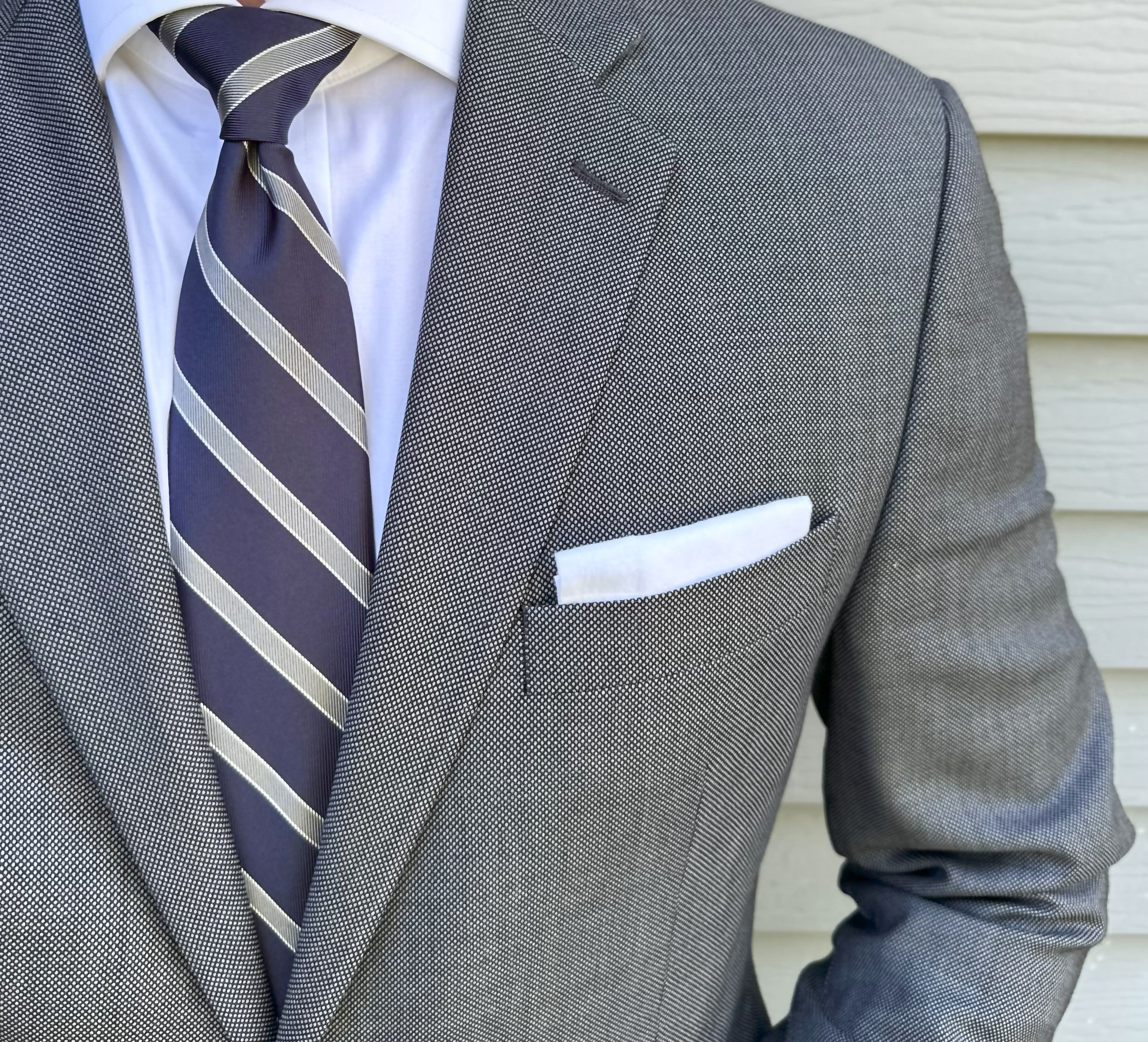 Navy striped silk necktie laid flat with the stripe repeat in view
