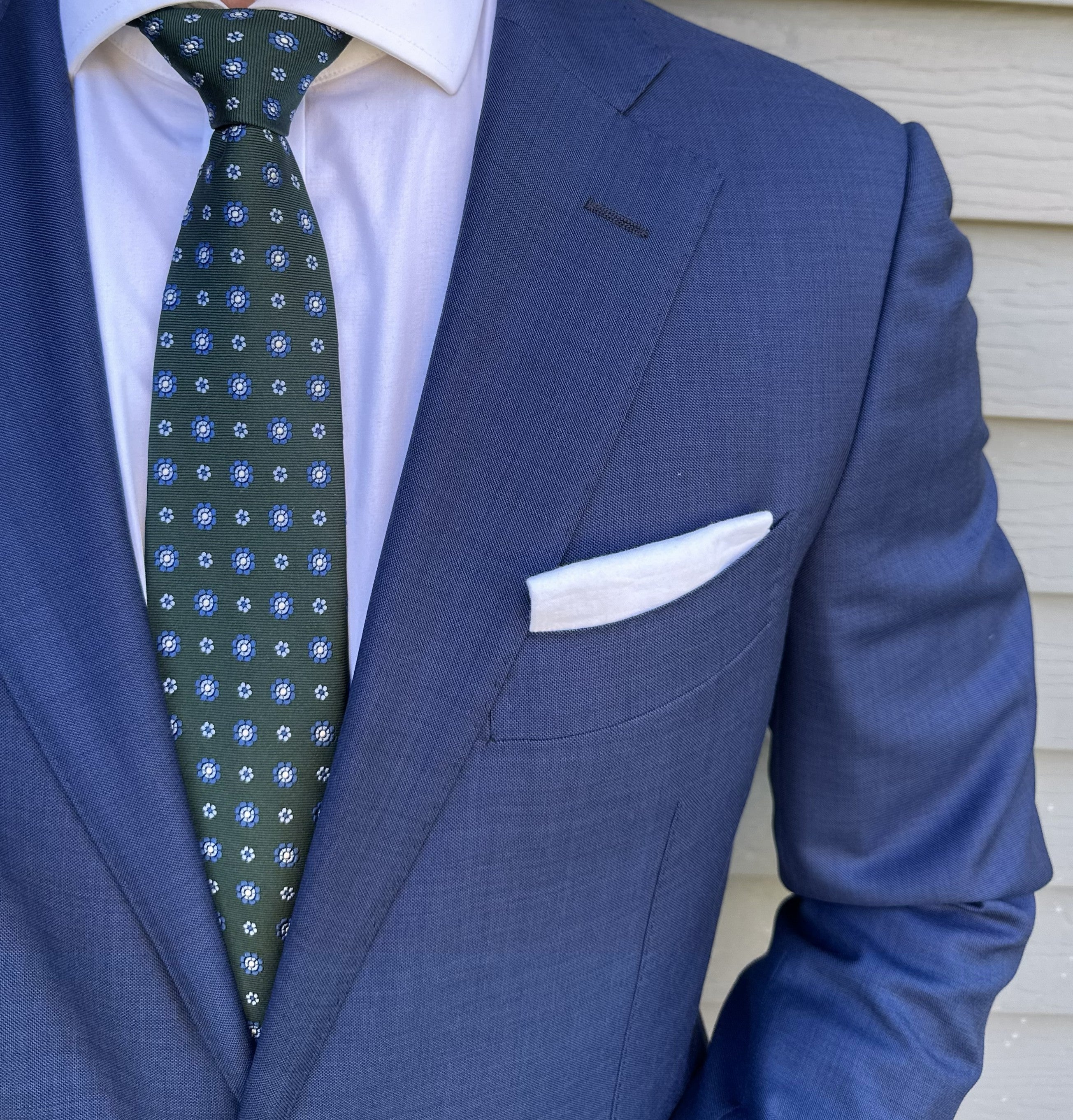 Dark green foulard silk necktie with a small repeating motif, flat